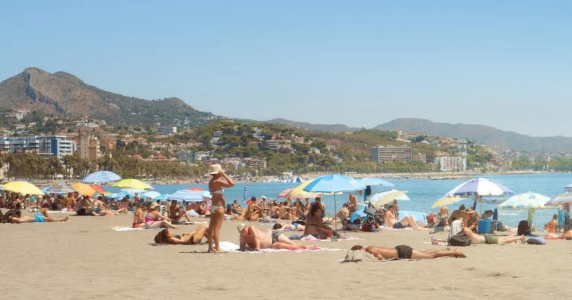 Sunny Malaga Beach with Sunbathers Umbrellas and Scenic Mountains
