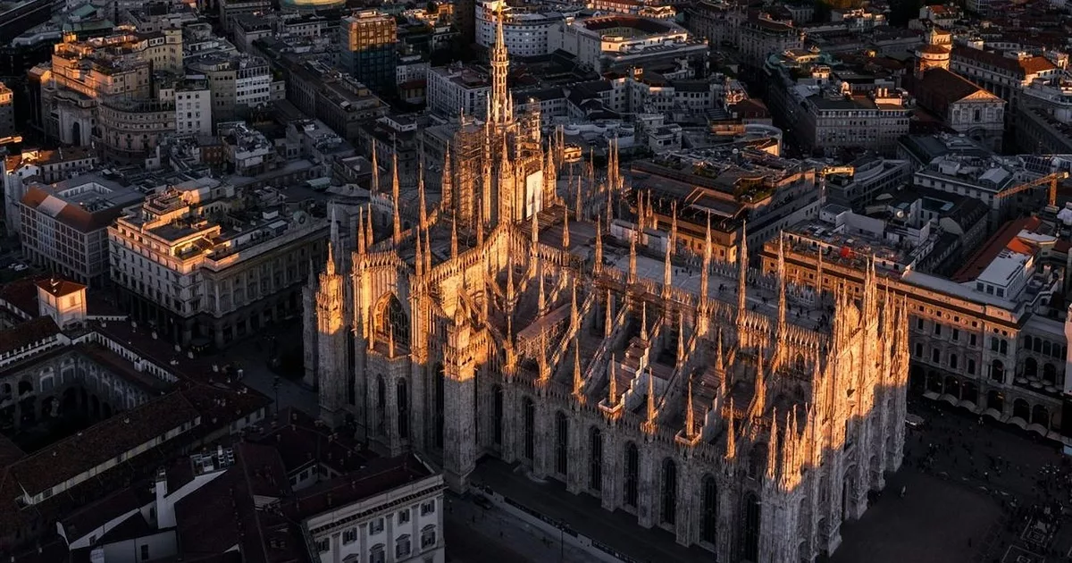 Duomo di Milano cathedral at sunset with golden light over cityscape