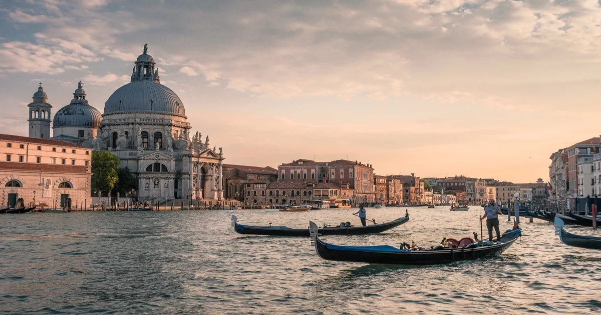 Traditional gondolas gliding through Venice’s Grand Canal at sunset