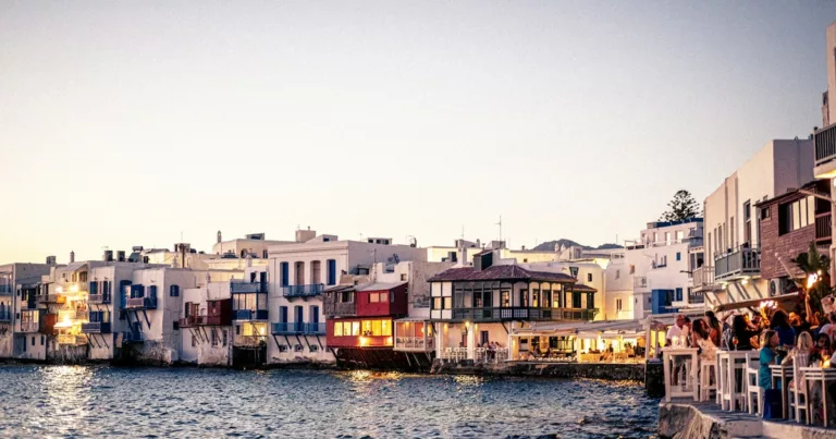 Sunset view of Mykonos waterfront with lively restaurants and bars by the sea in Greece