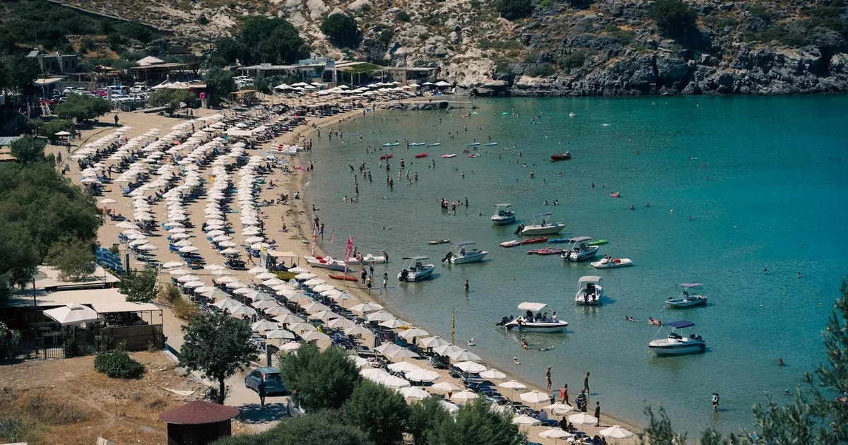 Sunbeds and boats lining the golden sandy shores of Rhodes beaches Greece