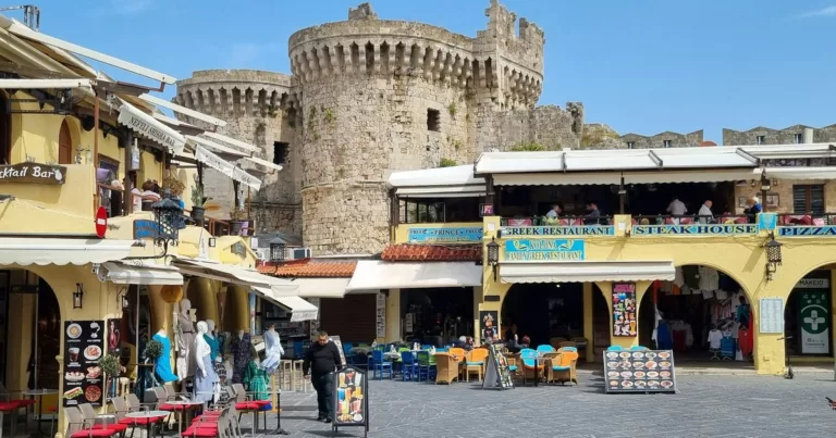 Colourful cafes and medieval castle walls in the heart of Rhodes Old Town Greece