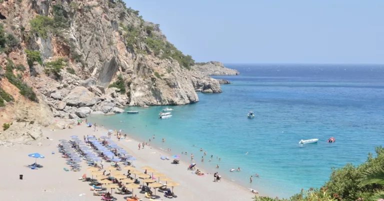 Tourists relaxing on the sunny Zakynthos beach with turquoise sea and cliffs