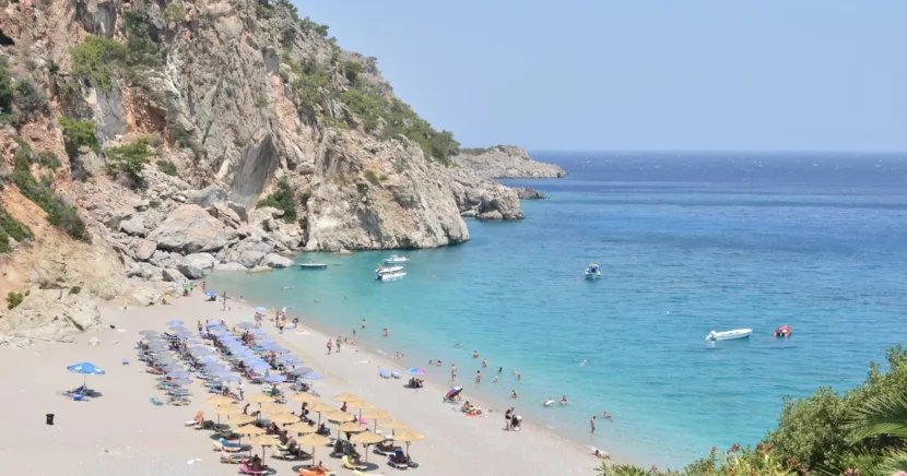 Tourists Relaxing on the Sunny Zakynthos Beach with Turquoise Sea and Cliffs